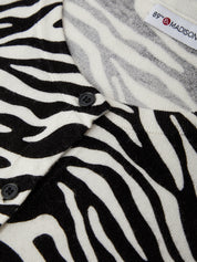 Close-up of zebra-patterned fabric with a button and visible brand label.