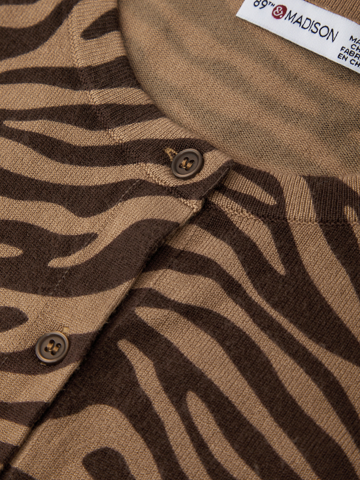 Close-up of a brown fabric with zebra pattern and a visible brand label.