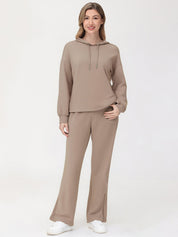 Woman wearing a beige hoodie and pants set on a white background