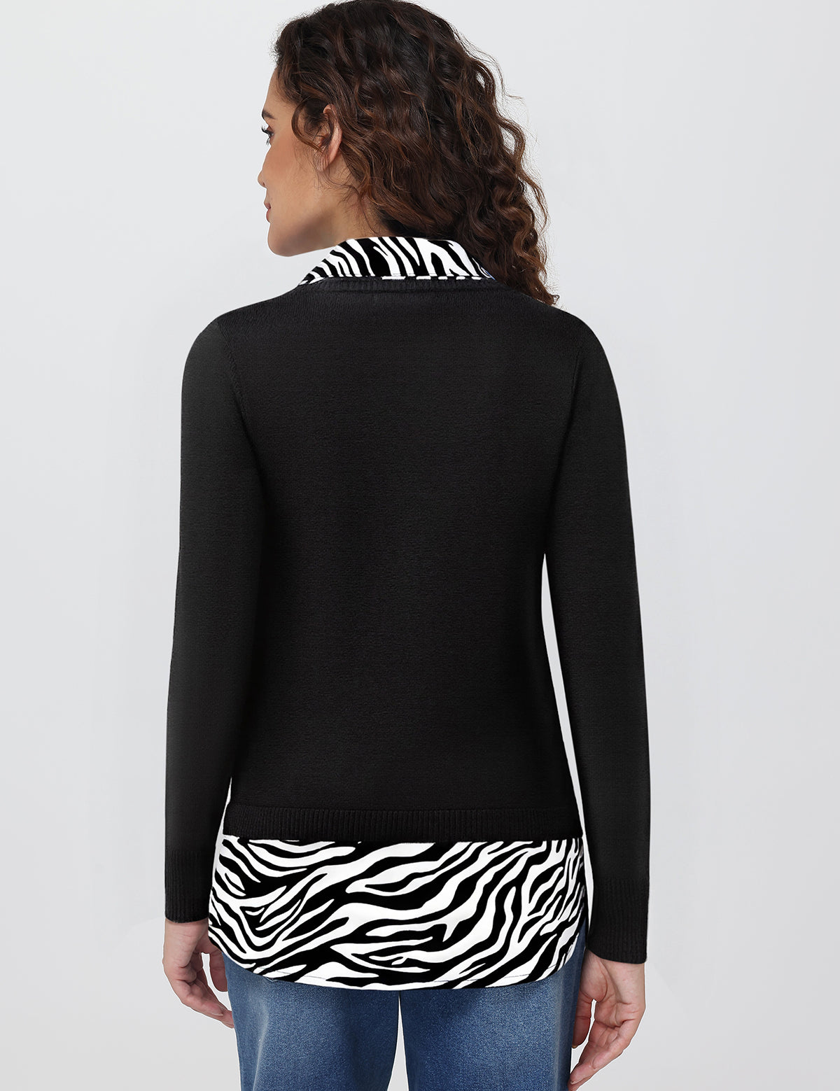 Woman wearing a black long-sleeve top with zebra print trim on a white background