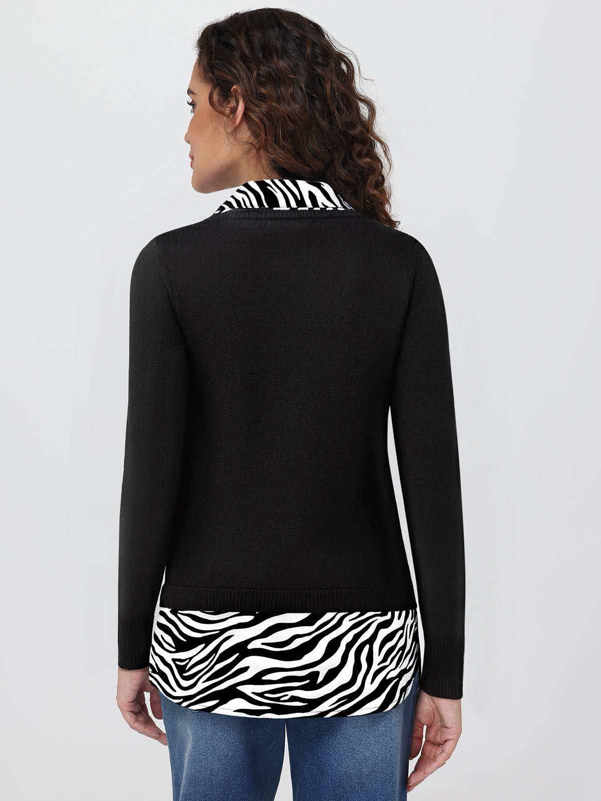 Woman wearing a black long-sleeve top with zebra print trim on a white background