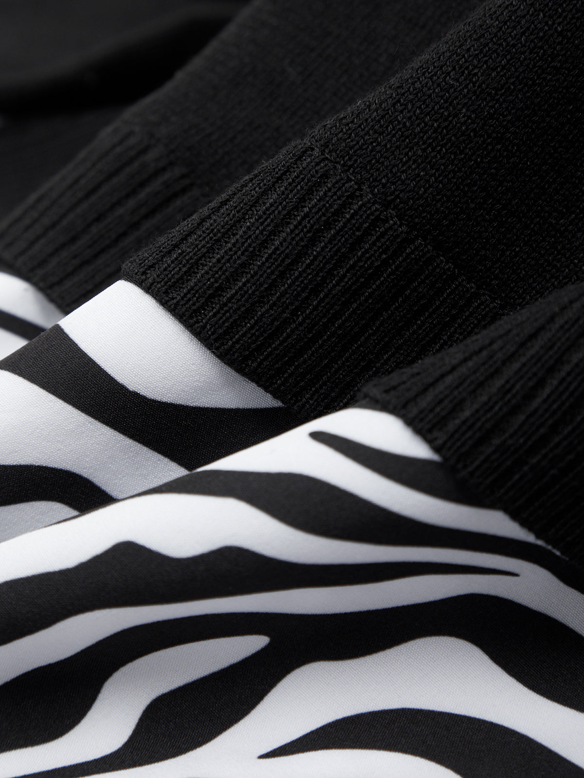 Close-up of black and white zebra-striped socks with a textured black sock on top.