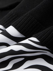 Close-up of black and white zebra-striped socks with a textured black sock on top.