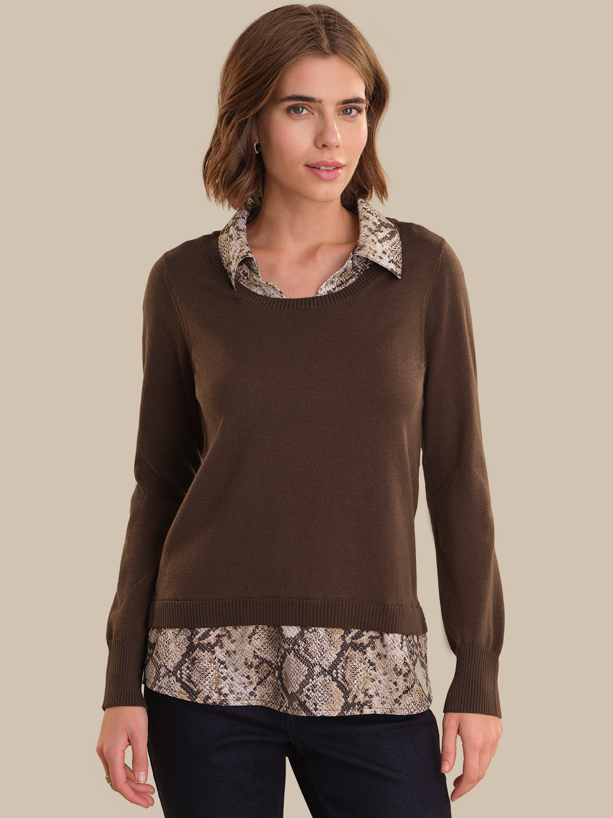 Woman wearing a brown sweater with snake print trim on a beige background