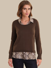 Woman wearing a brown sweater with snake print trim on a beige background