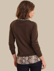 Woman wearing a brown sweater with snake print hem on a beige background