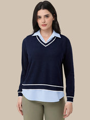A woman modeling a navy blue long-sleeve knit sweater with a light blue collar and hem detail, styled with olive green pants against a solid beige background.