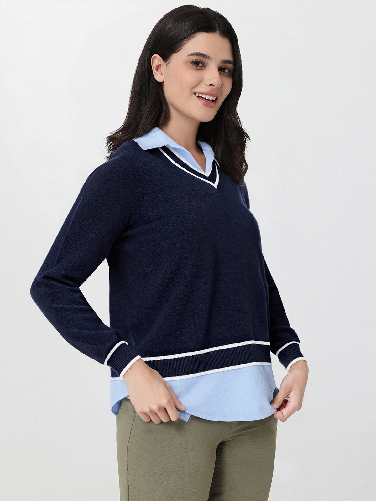 Woman wearing a navy sweater with a light blue collar and trim on a white background