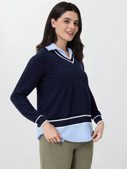 Woman wearing a navy sweater with a light blue collar and trim on a white background