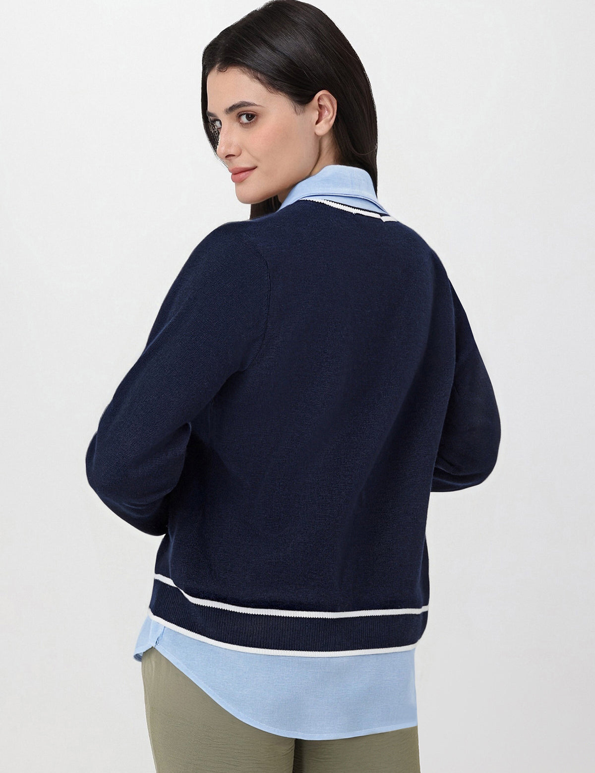 Woman wearing a navy blue sweater over a light blue shirt on a white background