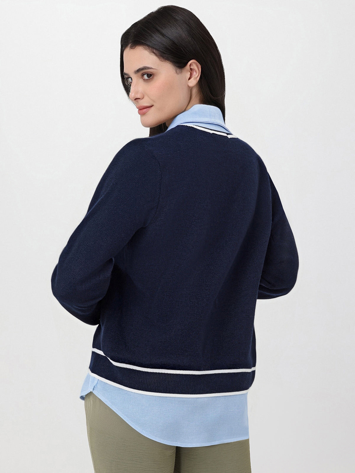 Woman wearing a navy blue sweater over a light blue shirt on a white background