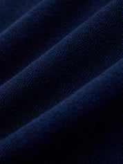 A close-up of dark navy blue knit fabric with soft diagonal folds showing the fine woven texture.