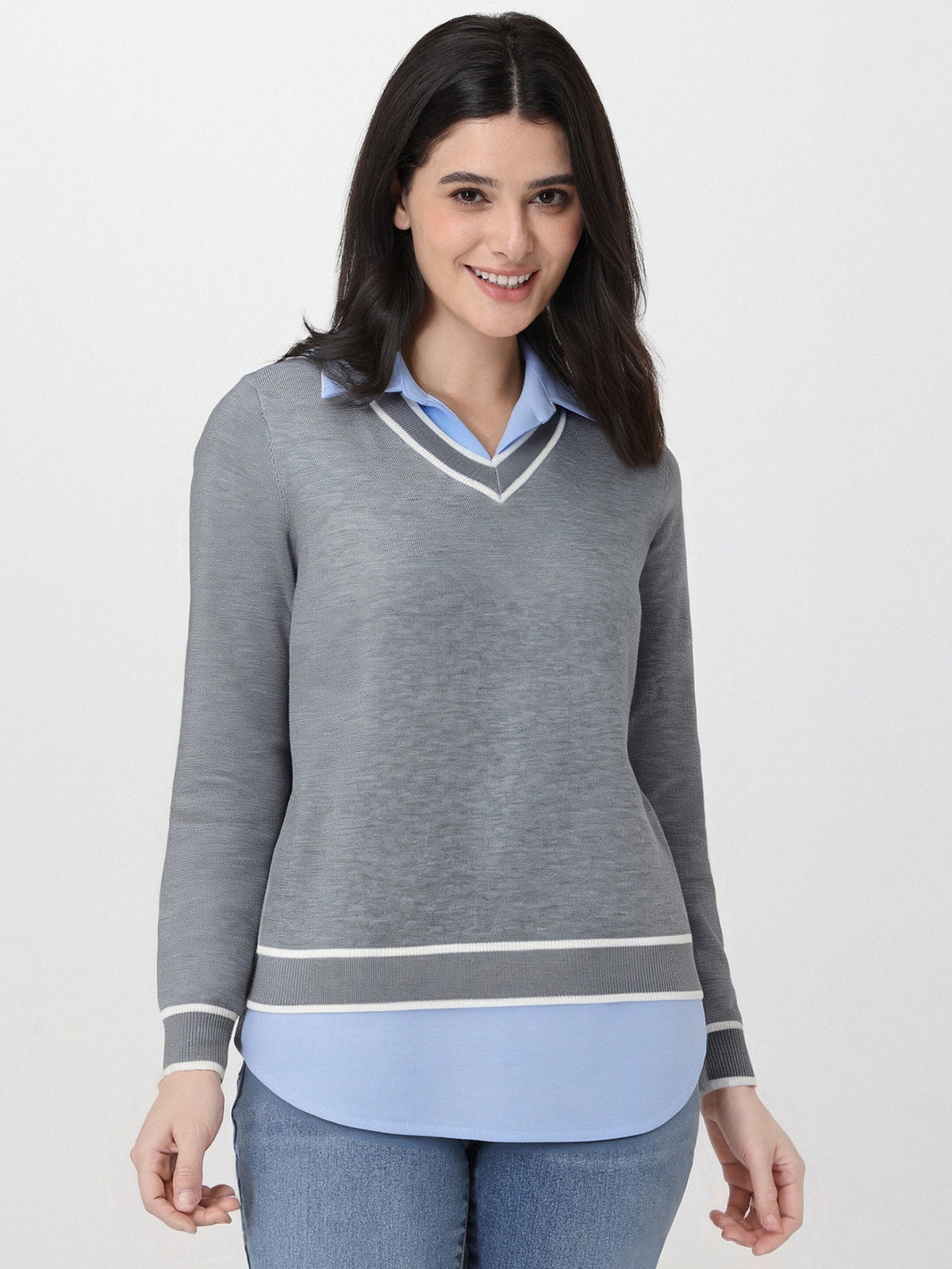 Woman wearing a gray sweater over a light blue shirt with a white background