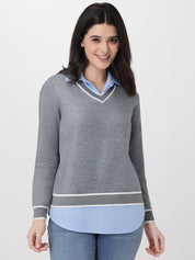 Woman wearing a gray sweater over a light blue shirt with a white background
