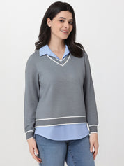 Woman wearing a gray sweater over a light blue shirt on a white background