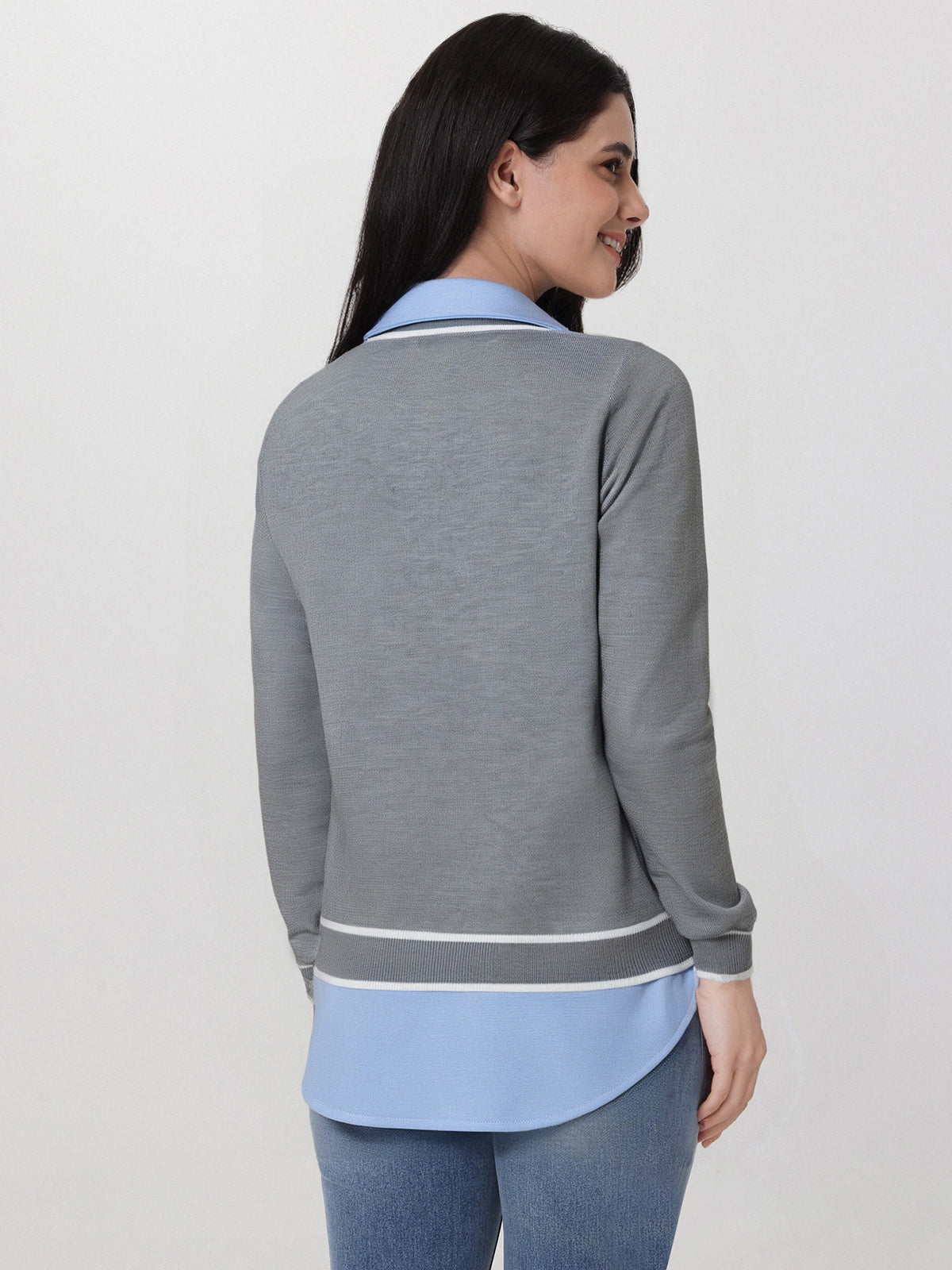 Woman wearing a gray and blue outfit with a plain background