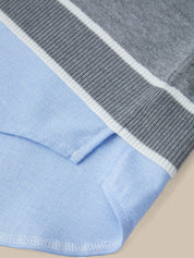 Close-up of a folded light blue knit garment, likely a sweater or knit top, showing a ribbed gray and white striped section along the edge.