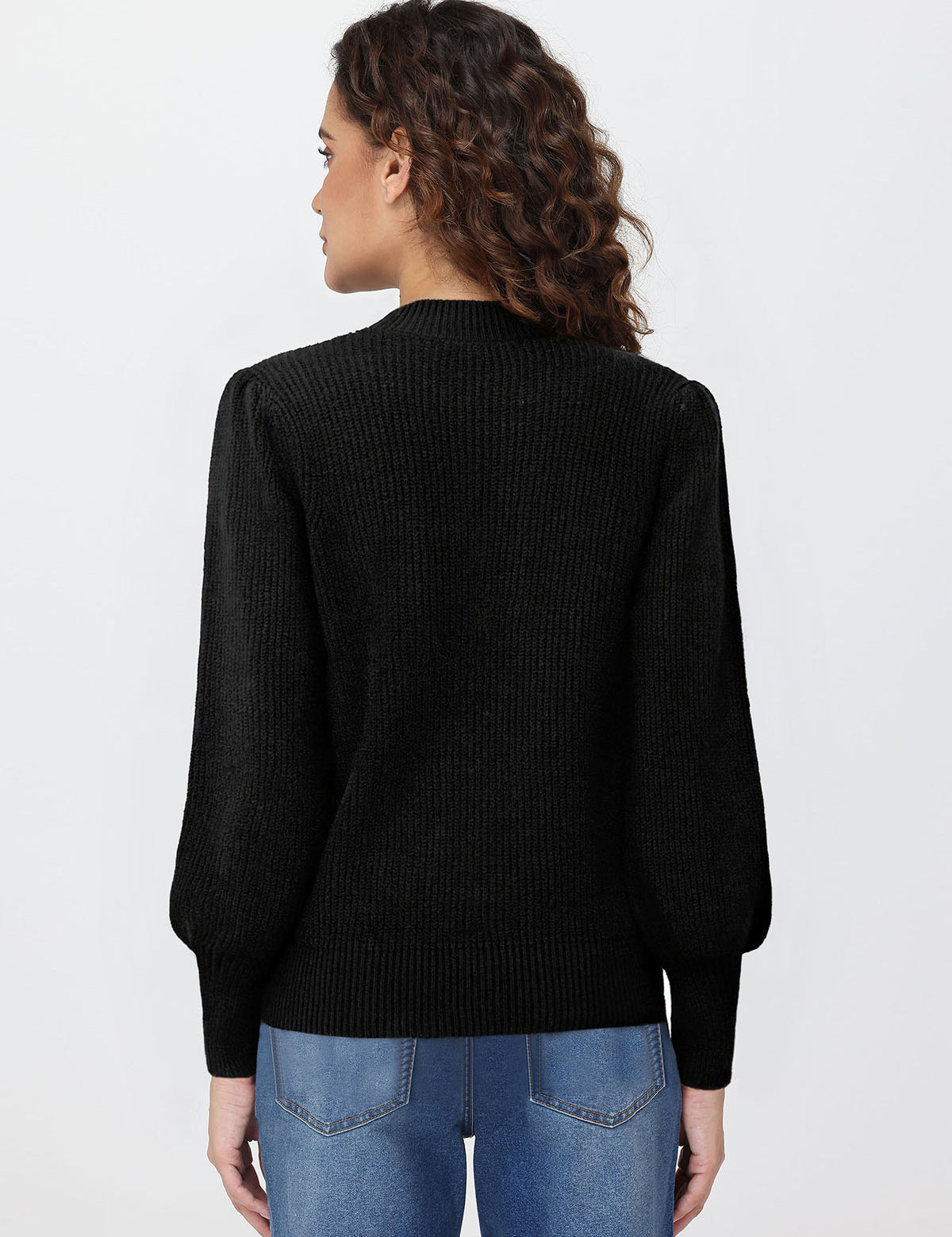 Person wearing a black sweater and blue jeans on a white background
