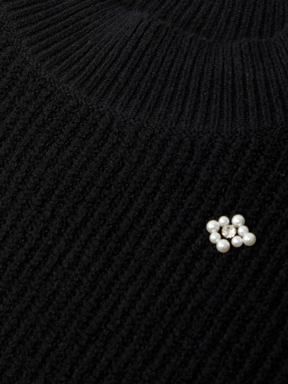 Close-up of a black knitted sweater with pearl embellishments.