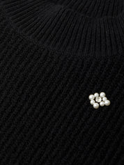 Close-up of a black knitted sweater with pearl embellishments.