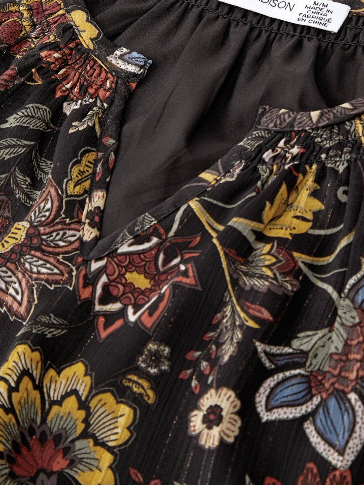 Black fabric with colorful floral patterns and a visible brand label.