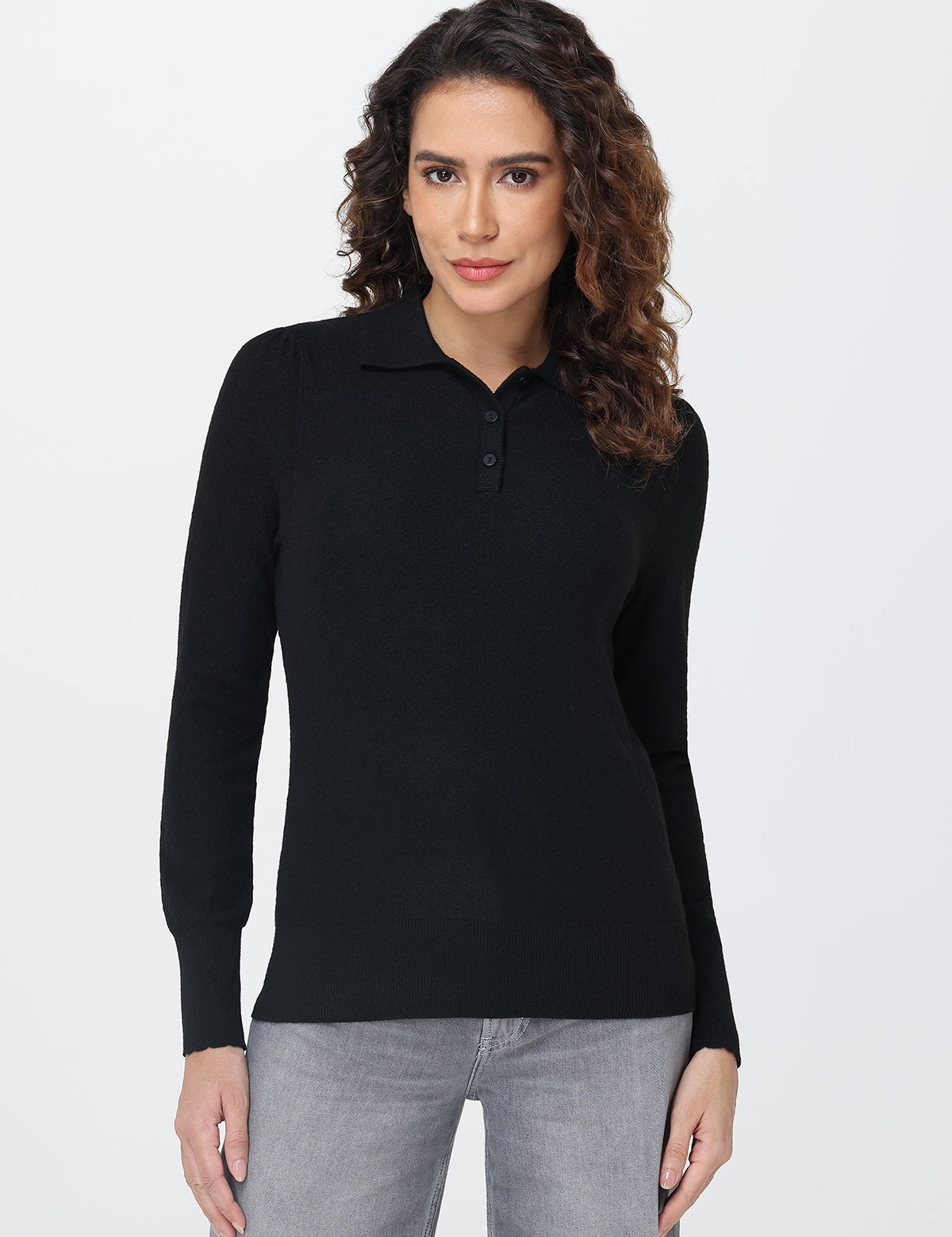 Woman wearing a black long-sleeve polo shirt against a white background
