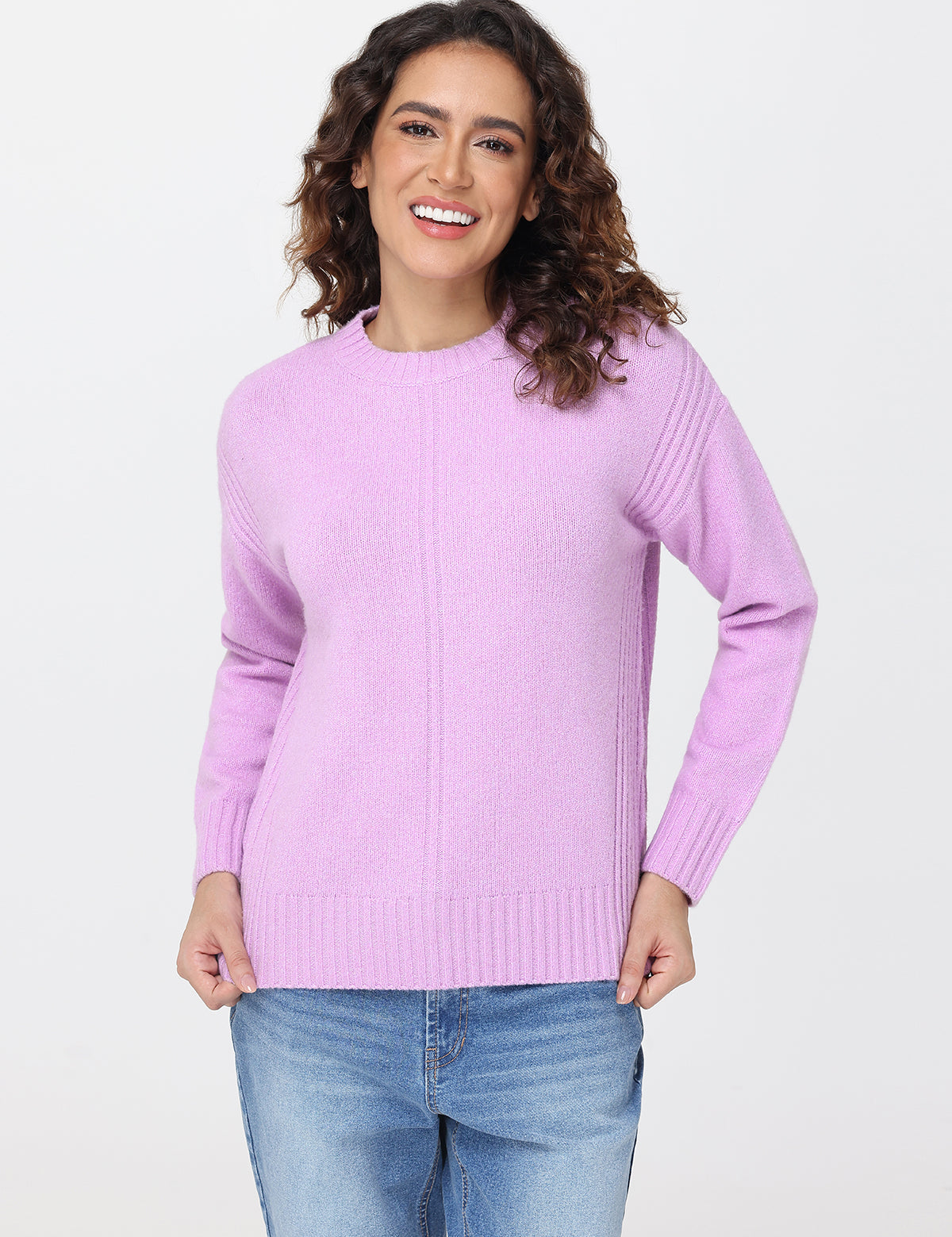 Woman wearing a light purple sweater and blue jeans on a white background