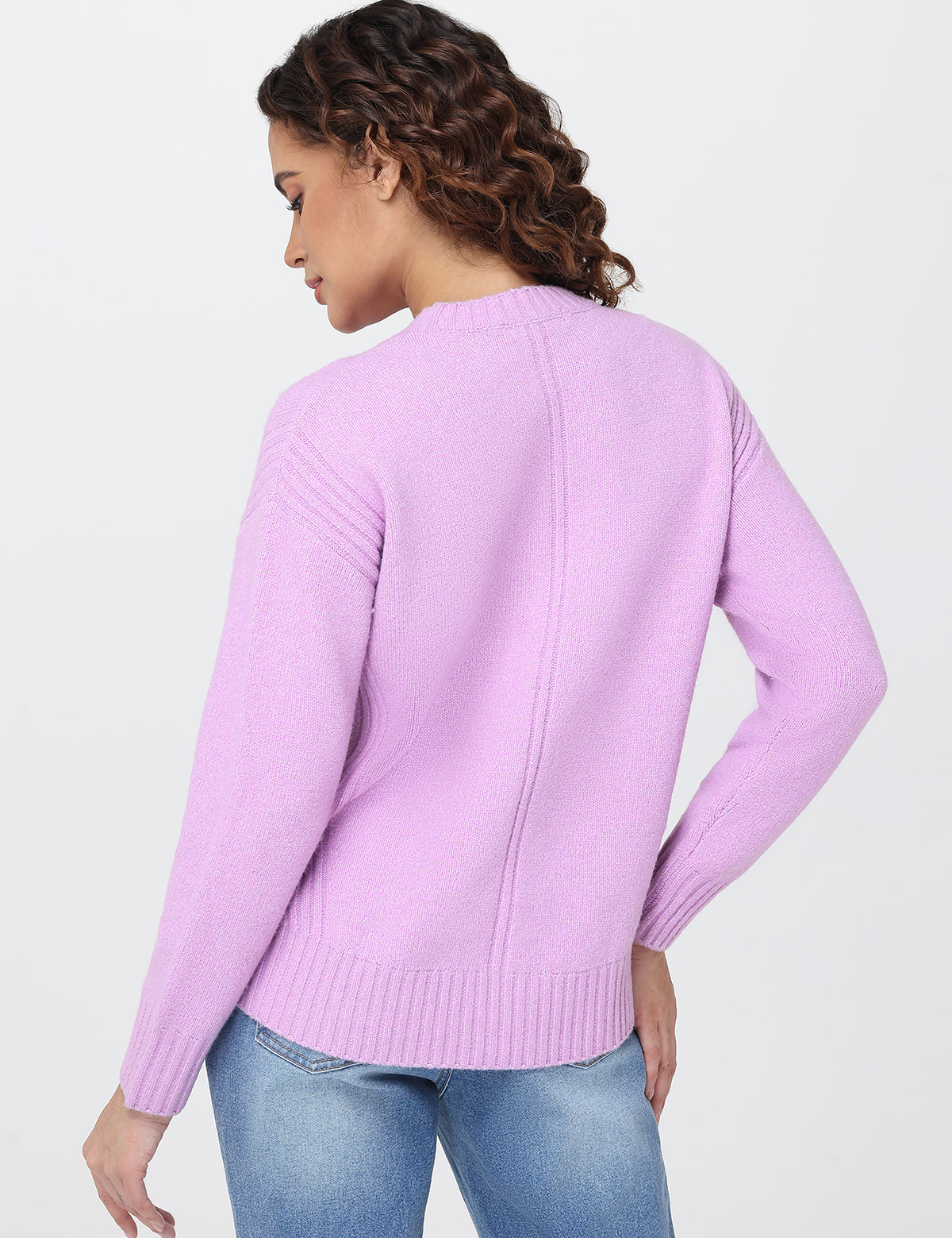 Woman wearing a light purple sweater and blue jeans on a white background