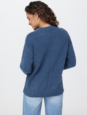 Woman wearing a blue sweater and light blue jeans on a white background