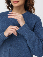 Close-up of a person wearing a blue sweater with a blurred background