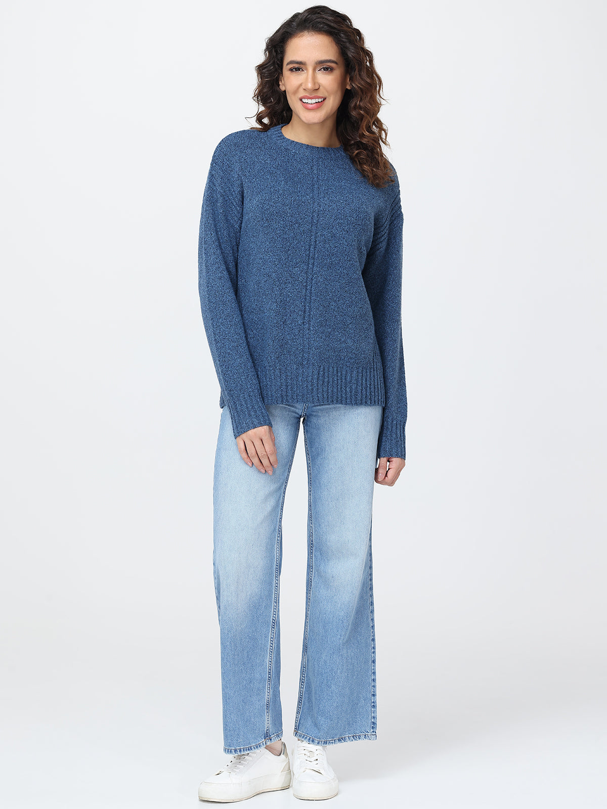 Woman wearing a blue sweater and light blue jeans on a white background