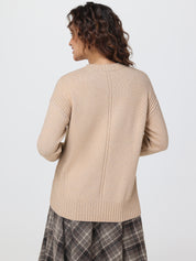 Woman wearing a beige sweater and plaid skirt on a white background