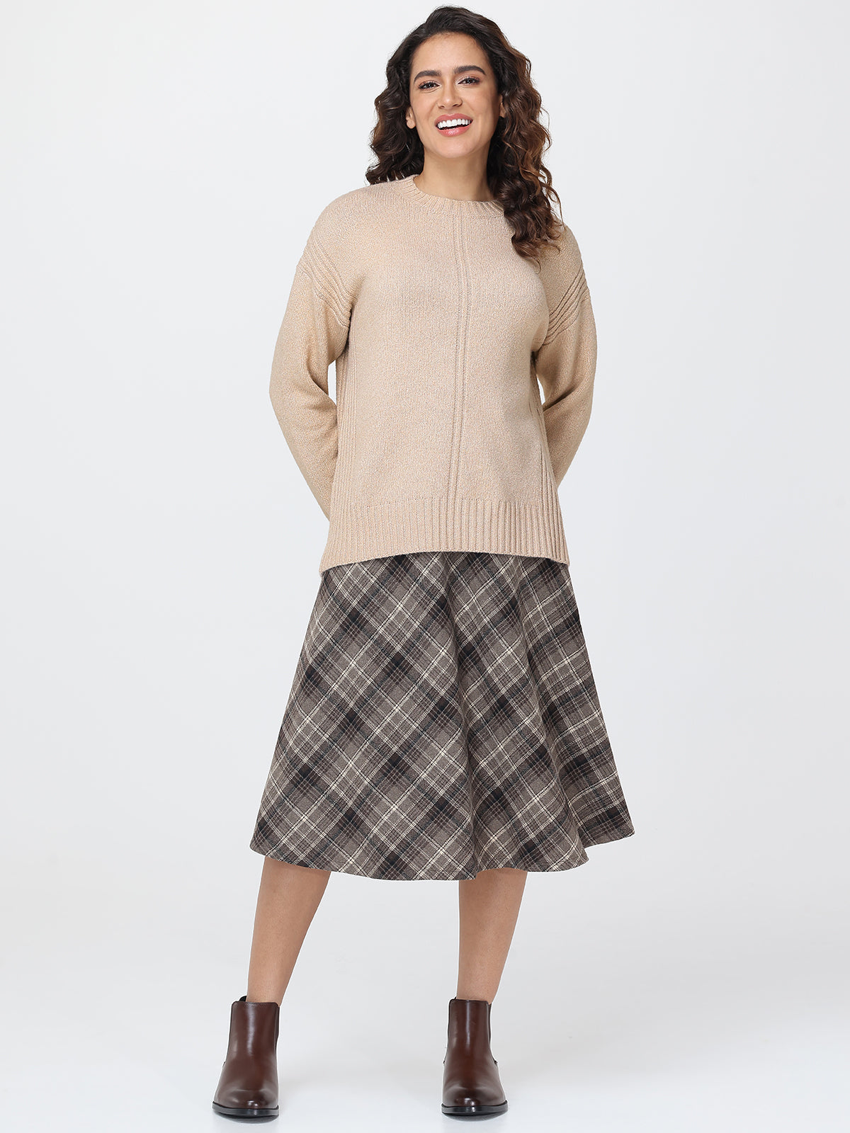 Woman wearing a beige sweater and plaid skirt on a white background