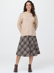 Woman wearing a beige sweater and plaid skirt on a white background