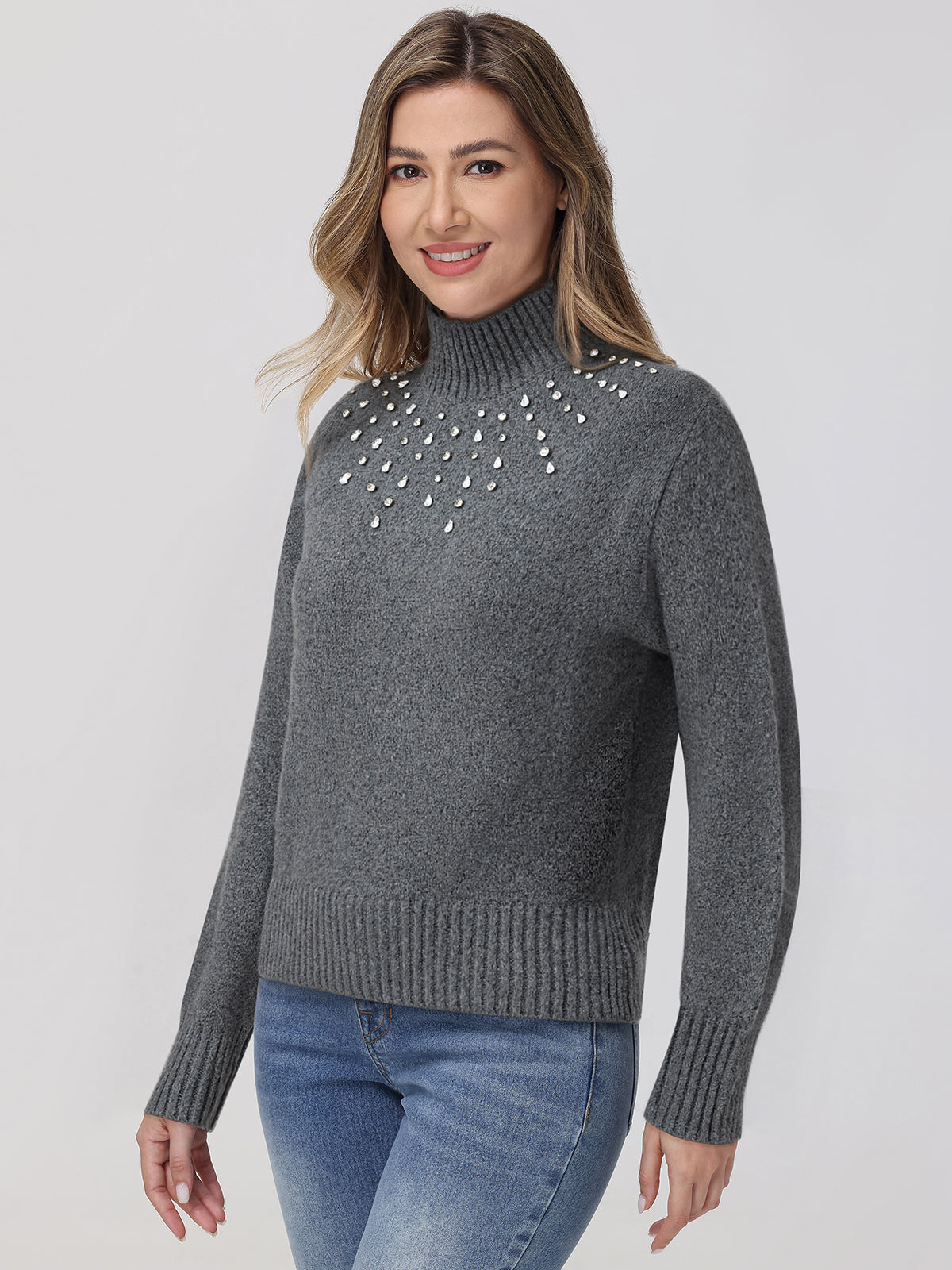 Woman wearing a gray sweater with decorative elements on a plain background