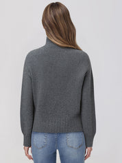 Person wearing a gray sweater and blue jeans on a light gray background