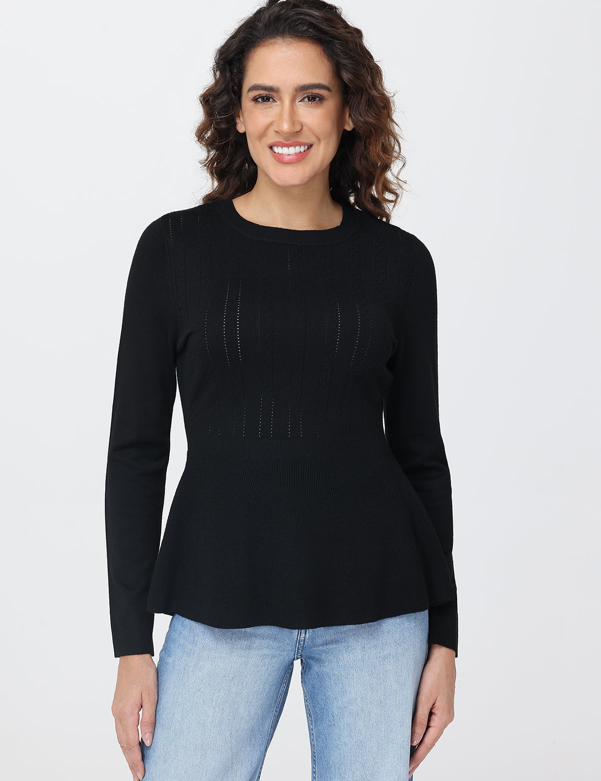 Woman wearing a black long-sleeve top and light blue jeans on a white background
