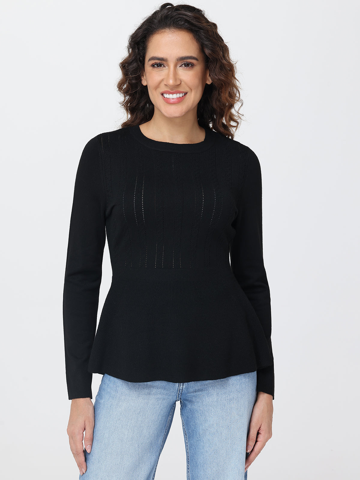 Woman wearing a black long-sleeve top and light blue jeans on a white background