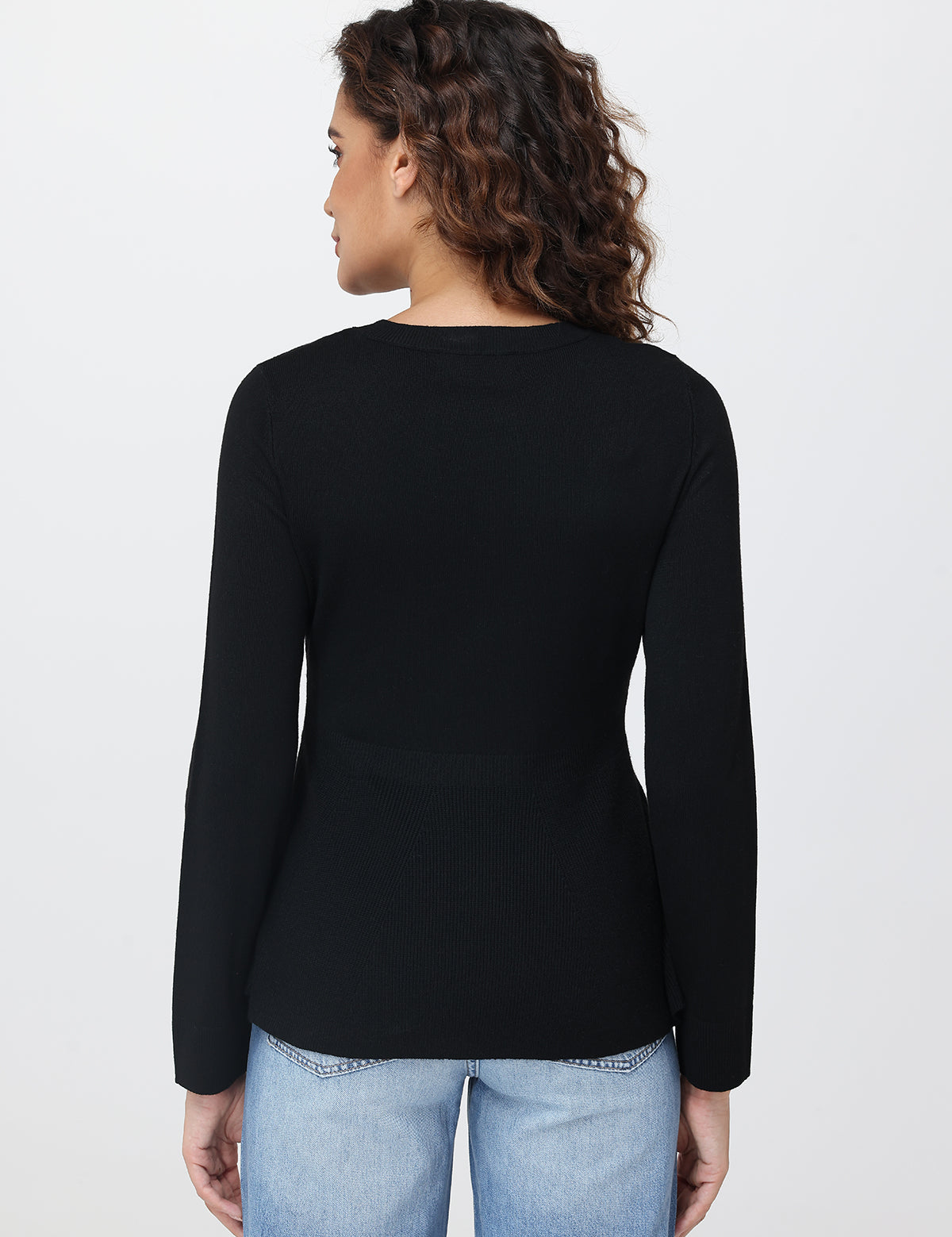 Person wearing a black long-sleeve top and light blue jeans on a white background