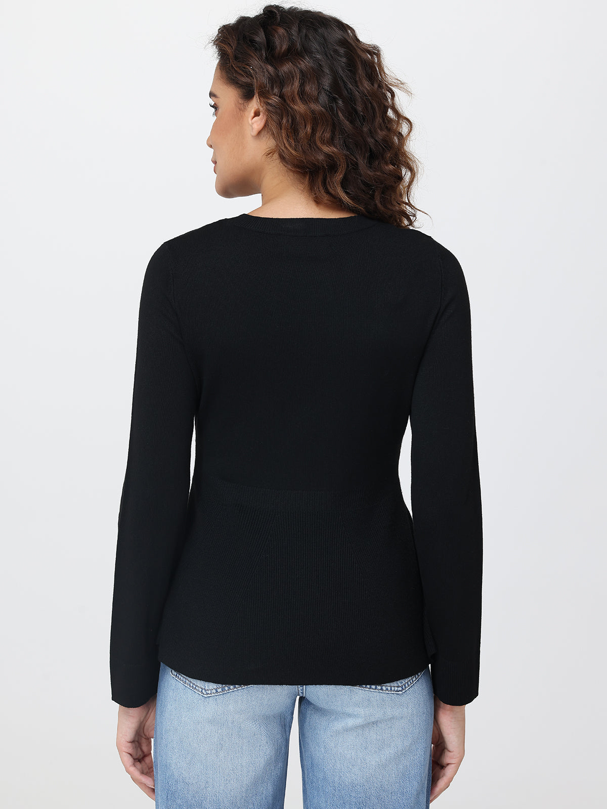 Person wearing a black long-sleeve top and light blue jeans on a white background