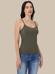 A woman modeling an olive green ribbed camisole tank top with thin shoulder straps, paired with blue jeans, against a solid beige background.
