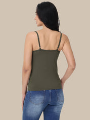 A woman shown from the back wearing an olive green spaghetti-strap tank top and blue jeans, set against a solid beige background.