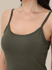 A close-up of a woman wearing a solid olive green camisole tank top against a neutral beige background.