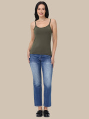 A woman modeling a sleeveless olive green camisole top paired with blue jeans and black flats, standing against a solid beige background.