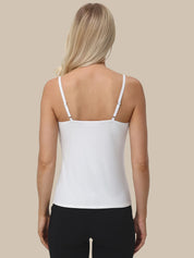 A woman shown from the back wearing a white spaghetti-strap camisole top and black pants, against a solid beige background.