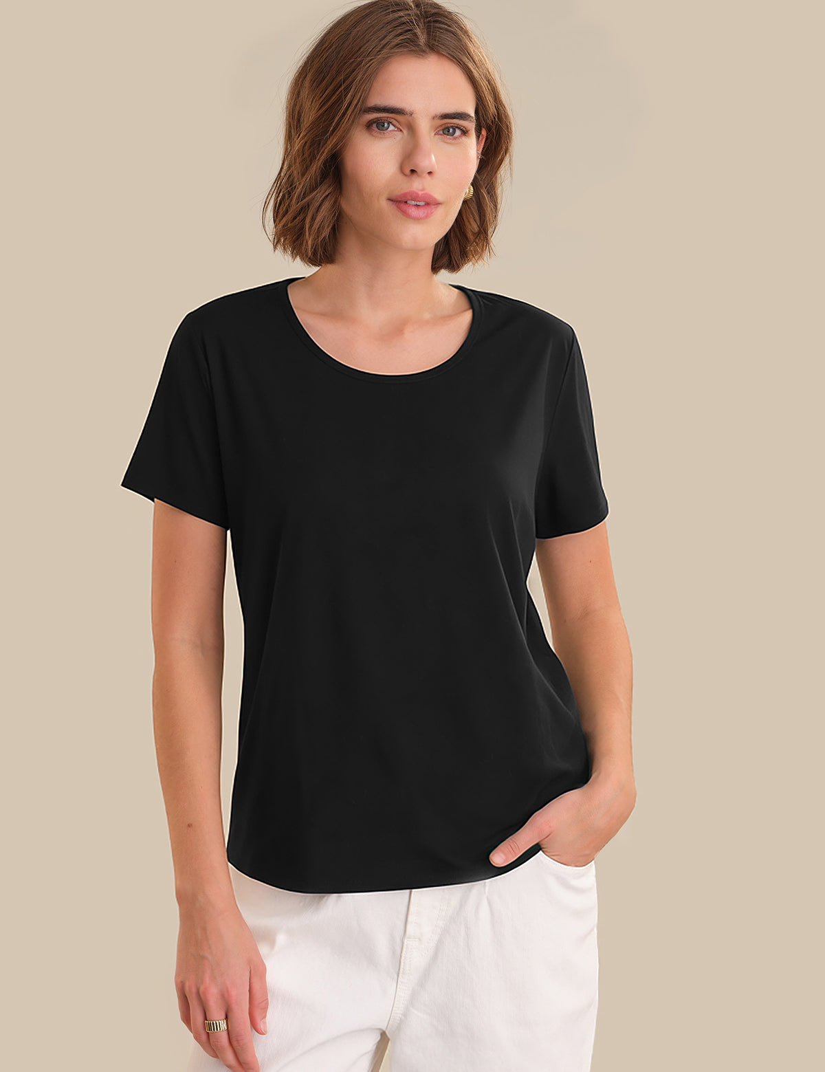 Woman wearing a black t-shirt and white pants against a beige background