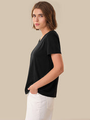 Woman wearing a black t-shirt and white pants against a beige background