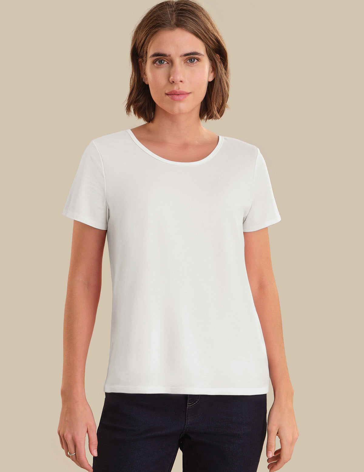 Woman wearing a plain white t-shirt against a beige background