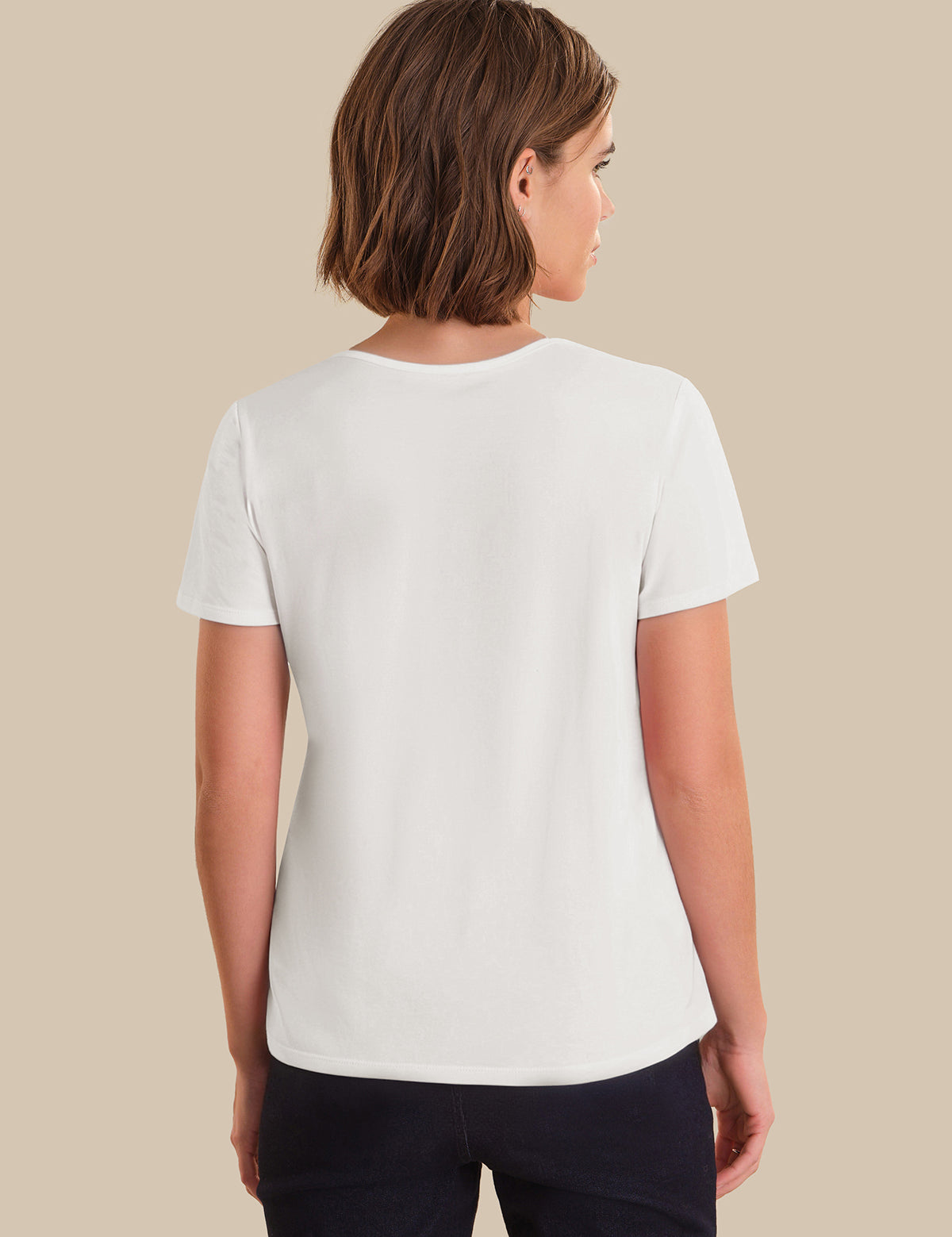 Woman wearing a plain white t-shirt against a beige background