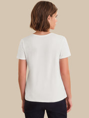 Woman wearing a plain white t-shirt against a beige background